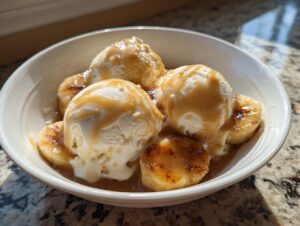 Three scoops of vanilla ice cream topped with caramelized bananas and rich sauce, classic Bananas Foster dessert.