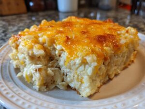 A close-up serving of creamy Chicken and Rice Casserole topped with melted, golden cheddar cheese.