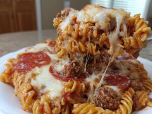 A fork lifts a cheesy, saucy portion of 1 pot pizza pasta, showing melted mozzarella strings.