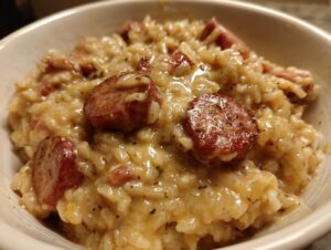 Close-up of creamy, cheesy sausage and rice dish topped with browned sausage slices.