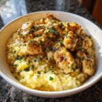 Close-up of juicy chicken scampi pieces served over creamy garlic parmesan rice, garnished with parsley.