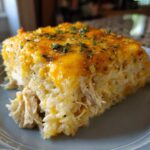 A close-up serving of creamy Chicken and Rice Casserole topped with melted cheddar cheese and parsley.