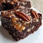 A decadent, fudgy square of turtle brownies topped with caramel, chocolate drizzle, and whole pecans.
