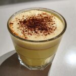 A creamy glass of homemade eggnog topped with frothy foam and dusted with cocoa powder.