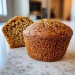 Close-up of a perfectly baked, moist bran muffin with one half cut to show the soft interior texture.
