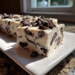 A thick, creamy slice of white Oreo fudge studded with dark chocolate cookie pieces, topped with crushed Oreo fudge.