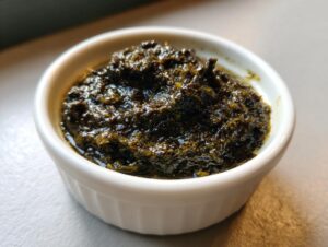 A close-up view of a rich, dark green olive dip texture in a small white ramekin.