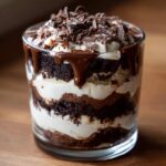 Close-up of a layered Baileys Chocolate Cheesecake Trifle with chocolate cake, cream, and chocolate shavings.