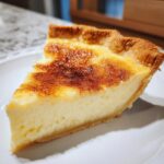 A close-up of a creamy slice of buttermilk pie with a golden, slightly browned top.