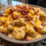A close-up shot of creamy crack chicken gnocchi coated in cheese sauce and topped with crispy bacon bits.