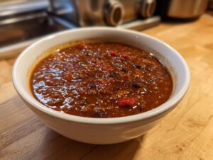 A close-up of a white bowl filled with rich, thick black bean soup, ready to eat.