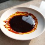 A close-up of thick, dark homemade teriyaki sauce pooled in a small white dish.