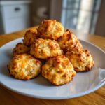 A stack of golden brown, cheesy bisquick sausage balls piled high on a light gray plate.