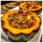 A close-up of a savory stuffed acorn squash half filled with rice, ground meat, and topped with pecans.