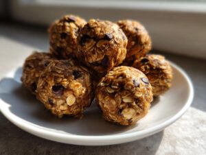 A stack of six homemade chocolate chip protein balls made with oats, sitting on a small white plate.