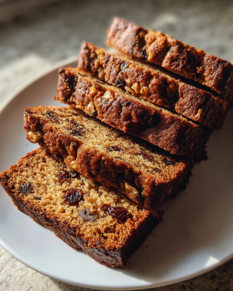 Close-up of several moist slices of date nut bread stacked on a white plate.