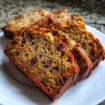 Close-up of several moist slices of date nut bread showing visible dates and walnuts on a white plate.