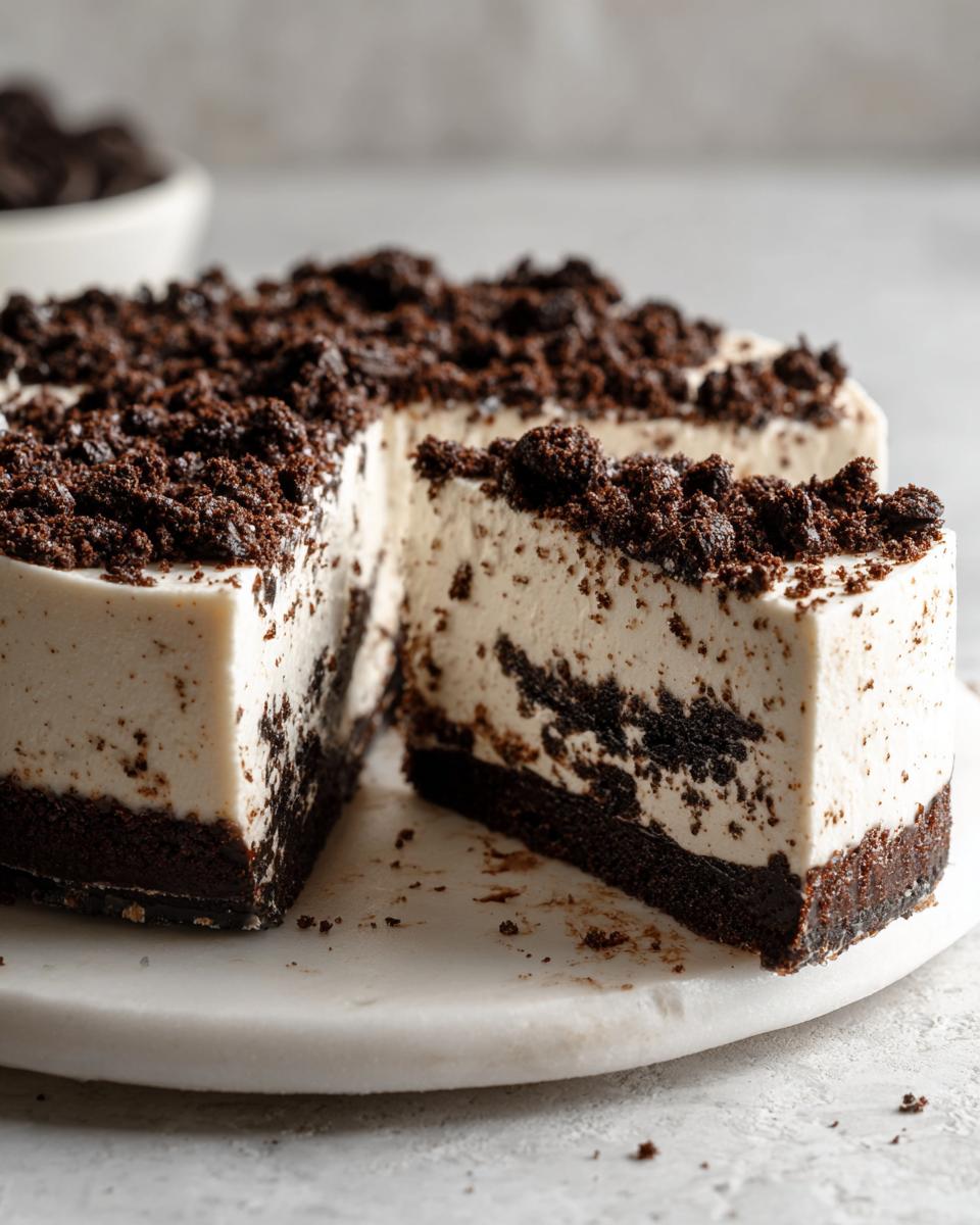 A close-up of a creamy no-bake Oreo cheesecake with a thick chocolate crust and generous crumb topping.