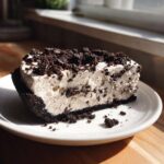 A generous slice of creamy, no-bake oreo pie with a dark chocolate crust and crushed topping.