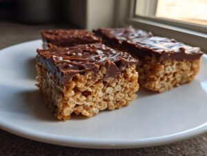 Three squares of rich peanut butter rice krispie treats topped with a thick layer of melted chocolate.