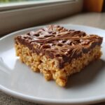 A single square of peanut butter rice krispie treats topped with swirled chocolate and peanut butter.