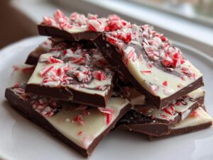 A stack of dark and white chocolate pieces topped with crushed candy canes from the peppermint bark recipe.