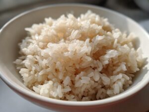 Close-up of perfectly cooked, fluffy sushi rice piled high in a small white bowl.