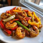 Close-up of seasoned shrimp fajitas with colorful bell peppers and onions served on a white plate.