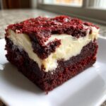 Close-up of a rich, layered red velvet brownies square with a thick cream cheese layer.
