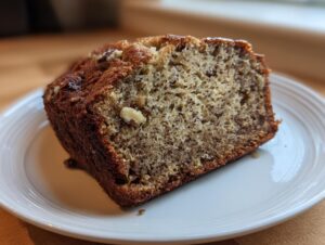 Close-up of a thick slice of moist sugar free banana bread showing the crumb texture and visible walnuts.
