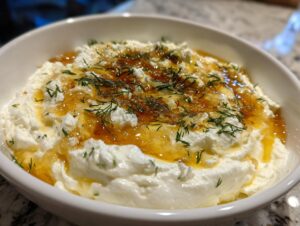 A close-up of creamy whipped feta dip topped with golden honey and fresh dill.