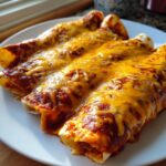 Close-up of three delicious cheese enchiladas covered in rich red sauce and melted cheddar cheese.