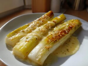 Three pieces of perfectly braised leeks topped with melted cheese and herbs, ready to eat.