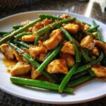Close-up of glazed chicken pieces mixed with bright green beans, showcasing the finished chicken and green beans skillet dish.