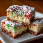 Close-up of stacked Christmas gooey butter cookies with a thick, creamy center and red and green sprinkles.