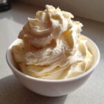 A close-up of creamy, swirled banana ice cream served in a small white bowl.