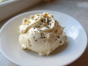A dollop of creamy white pizza sauce, seasoned with dried herbs and spices, served on a small white plate.