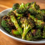 Close-up of perfectly seasoned and crispy roasted broccoli florets served in a white bowl.