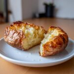 A perfectly cooked air fryer baked potato, split open to show the fluffy interior and crispy skin.
