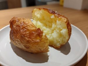 A perfectly cooked air fryer baked potato split open showing fluffy interior and salted, crispy skin.