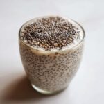 A glass filled with creamy chia seed pudding, topped generously with whole chia seeds.
