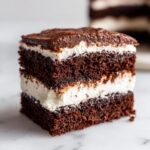 Close-up of a rich slice of Italian love cake showing three dark chocolate cake layers separated by thick white cream filling.