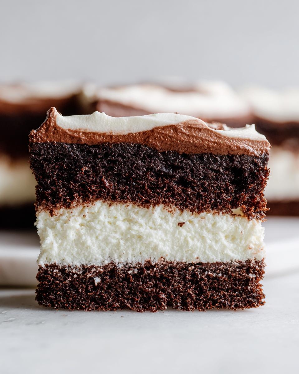 Close-up of a slice of amazing Italian love cake showing three distinct layers: dark chocolate cake, white creamy filling, and swirled chocolate frosting.