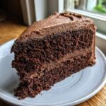 Close-up of a slice of very moist chocolate cake layered with chocolate frosting.