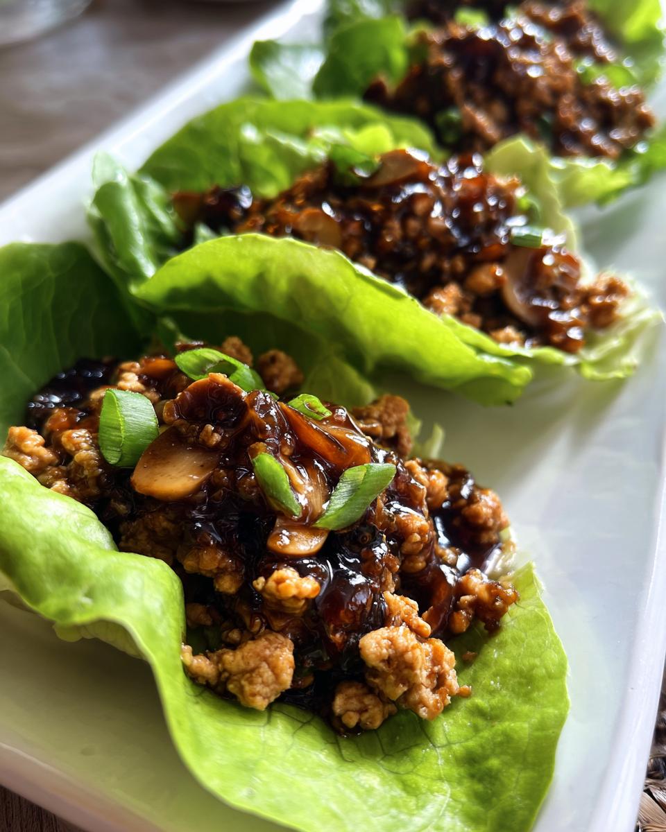 Close-up of three servings of delicious chicken lettuce wraps filled with savory ground chicken mixture and topped with green onions.