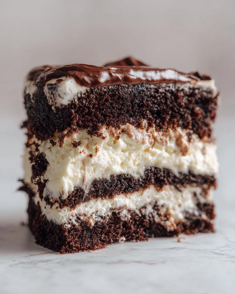Close-up of a decadent slice of layered italian love cake featuring dark chocolate cake, white cream filling, and chocolate ganache topping.