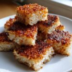 A stack of golden-brown, square pieces of crispy rice with a beautifully caramelized top layer.
