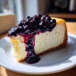 A rich slice of creamy blueberry cheesecake topped with glossy blueberry compote.