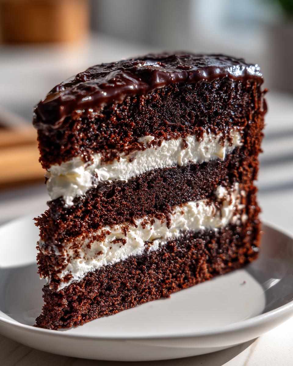 Close-up of a tall slice of brownie refrigerator cake with dark chocolate layers and white cream filling.