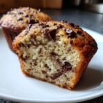 Close-up of a chocolate chip banana muffins cut in half, showing the moist crumb and melted chocolate.